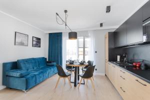 een woonkamer met een blauwe bank en een tafel bij Apartamenty Nord in Darlowko