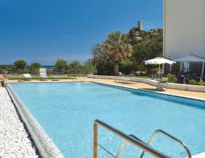 une grande piscine bleue dans un complexe hôtelier dans l'établissement Hotel Club Torre Salinas - Adults Only, à Muravera