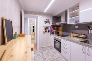 cocina con armarios blancos y suelo de madera en The Light appartment Tarragona, en Tarragona