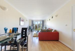 Una sala de estar con una mesa y un sofá rojo. en Hunters Wharf River View by Select SA, en Reading