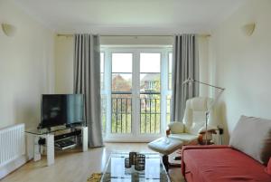 a living room with a red couch and a television at Hunters Wharf River View by Select SA in Reading