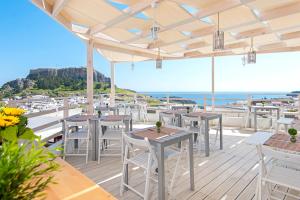 una terraza con mesas y sillas y el océano en Lindos Harmony Suites en Lindos