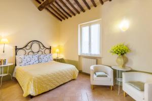 1 dormitorio con 1 cama, 1 silla y 1 ventana en La Chiocarella, en Pienza