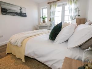 um quarto com uma cama branca com almofadas e uma janela em Badgers Way em Tintagel