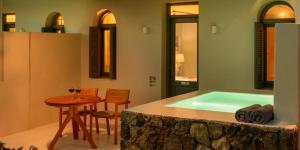 a bathroom with a bath tub with a table and a tablektop at Xenones Filotera in Imerovigli