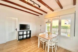 ein Esszimmer mit Tisch und Stühlen und einem Fernseher in der Unterkunft Alemanya 38 in Torroella de Montgrí