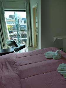 a bedroom with a large pink bed and a window at Alzira Plaza Hotel in São Lourenço