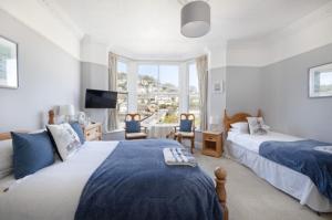 a bedroom with two beds and a television in it at Bridgeside Guest House in Looe