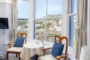 a living room with a table and chairs and a large window at Bridgeside Guest House in Looe