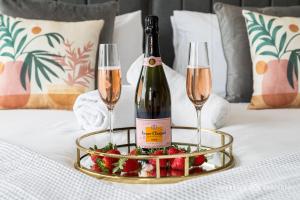 a bottle of champagne and two champagne glasses on a bed at BOURNECOAST - STYLISH FLAT with SEA GLIMPSES - FM8406 in Bournemouth