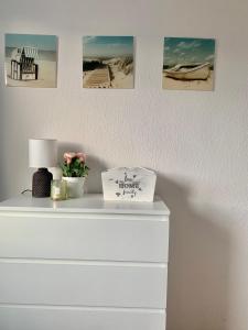 een witte dressoir met een lamp en foto's aan de muur bij Wera - klimatyczny apartament 300 m od plaży Brzeźno - AZW Gdańsk in Gdańsk