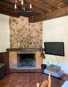 uma sala de estar com uma lareira de pedra e uma televisão de ecrã plano em Casa rural Adelaida em Villanueva del Conde