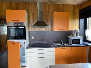 a kitchen with orange and white cabinets and a sink at L'évasion du berger australien in Couvin