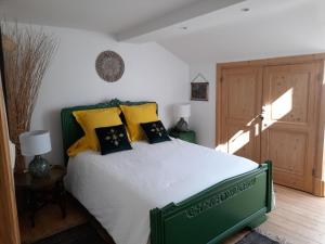 Un dormitorio con una cama verde con almohadas amarillas en LA KAIGA en Saint-Rambert-en-Bugey