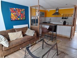 a living room with a couch and a kitchen at LA KAIGA in Saint-Rambert-en-Bugey