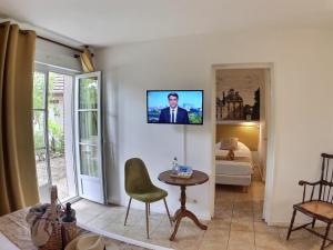 a living room with a television on a wall at Logis Hôtel du Château in Tour-en-Sologne