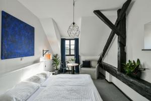 a white bedroom with a bed and a table at Hotel Pivoňka in Slavonice