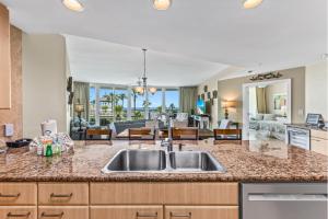 a kitchen with a sink and a living room at Caribe 212C in Orange Beach