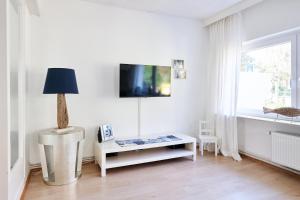 un soggiorno bianco con tavolo e lampada di Ferienwohnung Strand Bucht Moba-Travel a Lubecca