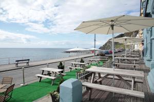 a row of picnic tables and umbrellas on a pier at The Glengower in Aberystwyth