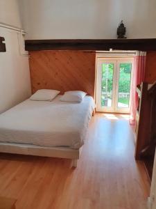 a bedroom with a bed and a large window at Le Moulin de Pommeuse in Pommeuse