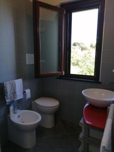 baño con aseo y lavabo y ventana en Open Space a due passi dal mare, en Ustica