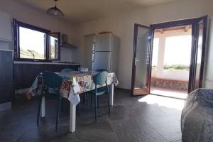 a kitchen with a table with chairs and a refrigerator at Open Space a due passi dal mare in Ustica +11 photos