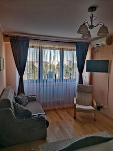a living room with a couch and a chair and a window at Apartament Select Mamaia in Mamaia