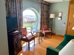 Habitación con sala de estar con TV y ventana. en Parador de Salamanca, en Salamanca