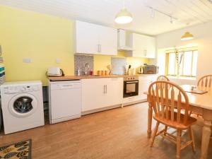 a kitchen with white cabinets and a table and chairs at The Pool House in Norwich