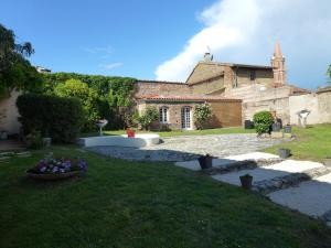 a stone building with a yard with flowers in the grass at Logis Hôtel L'Arche de Noé in Noé