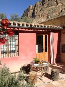 ein rotes Haus mit einem Tisch davor in der Unterkunft Casica de Perintín Cottage in Ricote