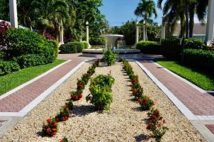 a garden with red flowers and a fountain at Serenity at Seascape: Steps to the beach & Shops in Palm Beach Shores