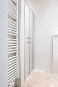 a glass shower in a white bathroom with white shutters at Prorsus Design Apartments in Leipzig