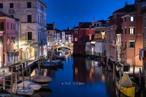 a canal with boats in a city at night at Palazzo Baffo - Residenza storica , Chioggia in Chioggia