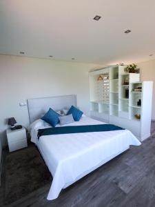 sypialnia z dużym białym łóżkiem z niebieskimi poduszkami w obiekcie Vаrаndаs dо Sоl-Vista relaxante entre mar e montanha w mieście Ponta do Sol
