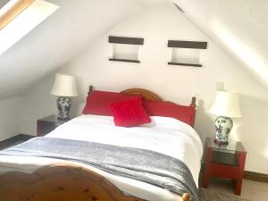 a bedroom with a bed with red pillows on it at The Old Stables in Swansea