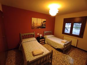 2 camas en una habitación con paredes rojas en Casa Ángeles, en Beceite
