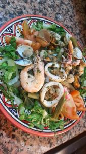 a bowl of salad with shrimp and vegetables on a table at Imsouane soul lodge in Imsouane