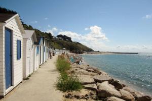 una acera junto a una playa con edificios y agua en NOUVEAU gîte situé au coeur du cotentin, en Saint-Pierre-dʼArthéglise