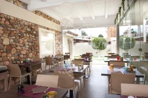 a restaurant with tables and chairs and a stone wall at Suimi's Hotel in Villasimius