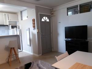 un soggiorno con porta, tavolo e TV di Agréable F2, jardin, garage, fibre, clim ch a Fort-de-France