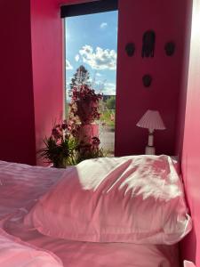 Habitación de color rosa con cama y ventana en B&B Fryden Ly en Horsens