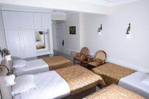 a room with three beds and a table and chairs at Hali Hotel in Istanbul
