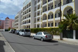 a row of cars parked in front of a building at Apartamento Eden in Monte Gordo