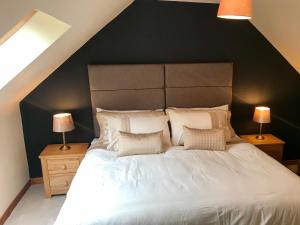a bedroom with a large white bed with two lamps at Lindfields in Inverness