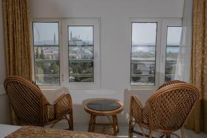 a bedroom with three windows and a table and chairs at Hali Hotel in Istanbul