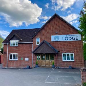 New Forest Lodge في Landford: مبنى من الطوب الأحمر مع علامة تقرأ نزل بيتي