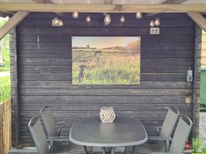 un patio con mesa y sillas con una foto en la pared en Schwone Diekhuusje - Vakantiewoning aan de Noordzeekust, en Schoondijke