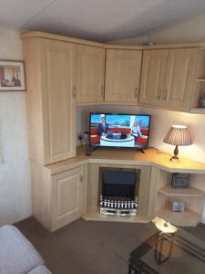 a living room with a tv on a desk with a fireplace at Annandale skegness in Skegness
